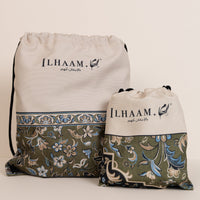 Two drawstring storage bags from LHAAM, one larger and one smaller, featuring a cream top half with black branding and a green patterned bottom half with blue and beige floral motifs.