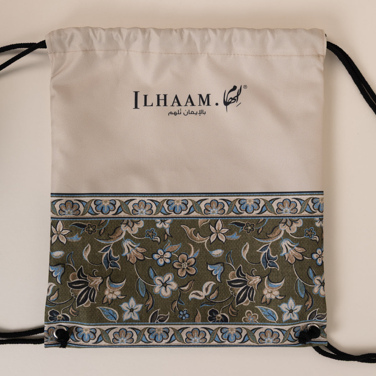 An off-white drawstring bag with a decorative border and black drawstrings, featuring the brand name 'ILHAAM' printed on the front, set against a plain beige background.