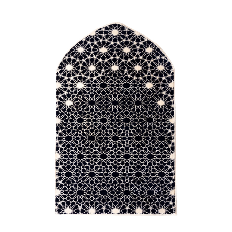 Islamic prayer rug with arched mihrab shape and black and white geometric pattern on a white background
