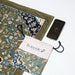 Islamic travel prayer set with rawdah design prayer mat, drawstring pouch and smartphone showing qibla direction 