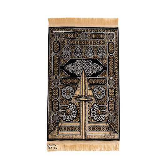 Black and gold prayer rug inspired by the door of the Kaaba featuring intricate Islamic patterns and fringe detail
