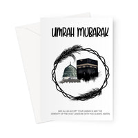 Islamic Umrah greeting card featuring a circular black wreath design with illustrations of the Kaaba and Masjid an-Nabawi, with the message “Umrah Mubarak”, designed by Ilhaam